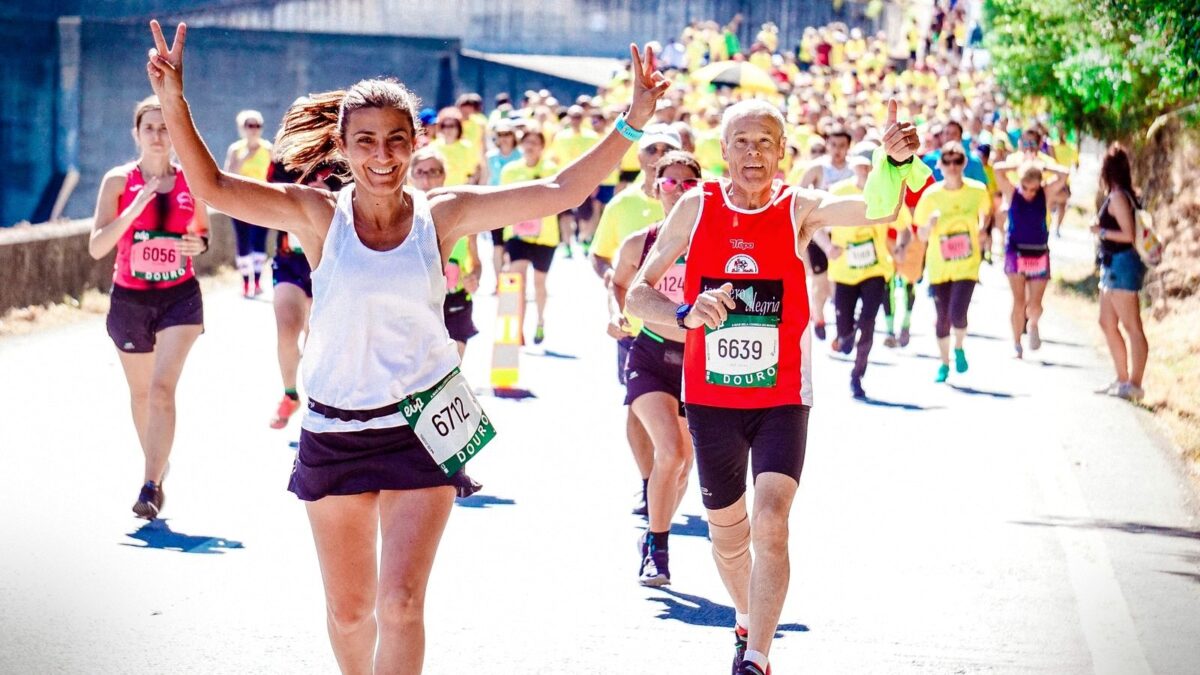 Läufergruppe beim Firmenlauf in Sportshirts mit Startnummern, jubelnde Frau und Mann mit Daumen hoch